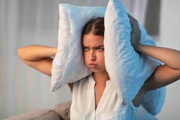 woman holding pillows over ears
