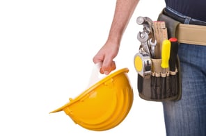 worker wearing tool belt and holding yellow construction hat