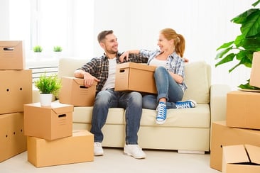 Man and woman sitting on couch with packed boxes around them