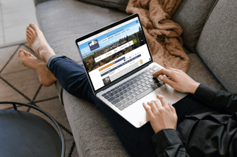 Woman using MacBook Pro lying on the couch near the blanket