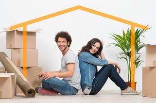 man and woman sitting back to back surrounded by moving boxes