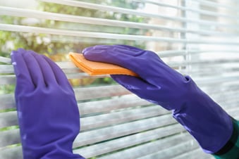 a person cleaning blinds in an apartment